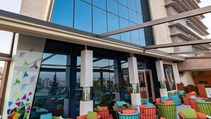 Ein modernes Gebäude mit Glasfassade und einer Außenbereichs-Sitzgelegenheit mit bunten Stühlen und Tischen.