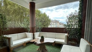 A modern outdoor seating area with a brick column, white sofas, and a wooden table. - Beautiful atypical loft with Jacuzzi (Tarascon)