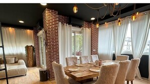A dining area with a brick wall, wooden floor, and a round table with chairs. - Beautiful atypical loft with Jacuzzi (Tarascon)