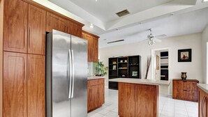 Une cuisine moderne avec des meubles en bois, un réfrigérateur en acier inoxydable et un îlot central.