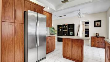 A modern kitchen with wooden cabinets, a stainless steel refrigerator, and a central island.
