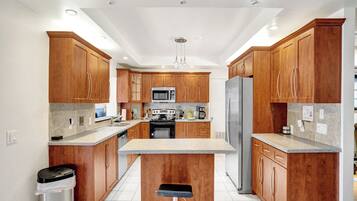 A modern kitchen with wooden cabinets, stainless steel appliances, and a central island.