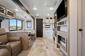 A compact RV interior with a kitchenette, seating area, and a TV mounted on the wall. - Joy Drive In Movie & RV Resort - Puma - Joy Drive In Movie & RV Resort - Puma (Copperas Cove)