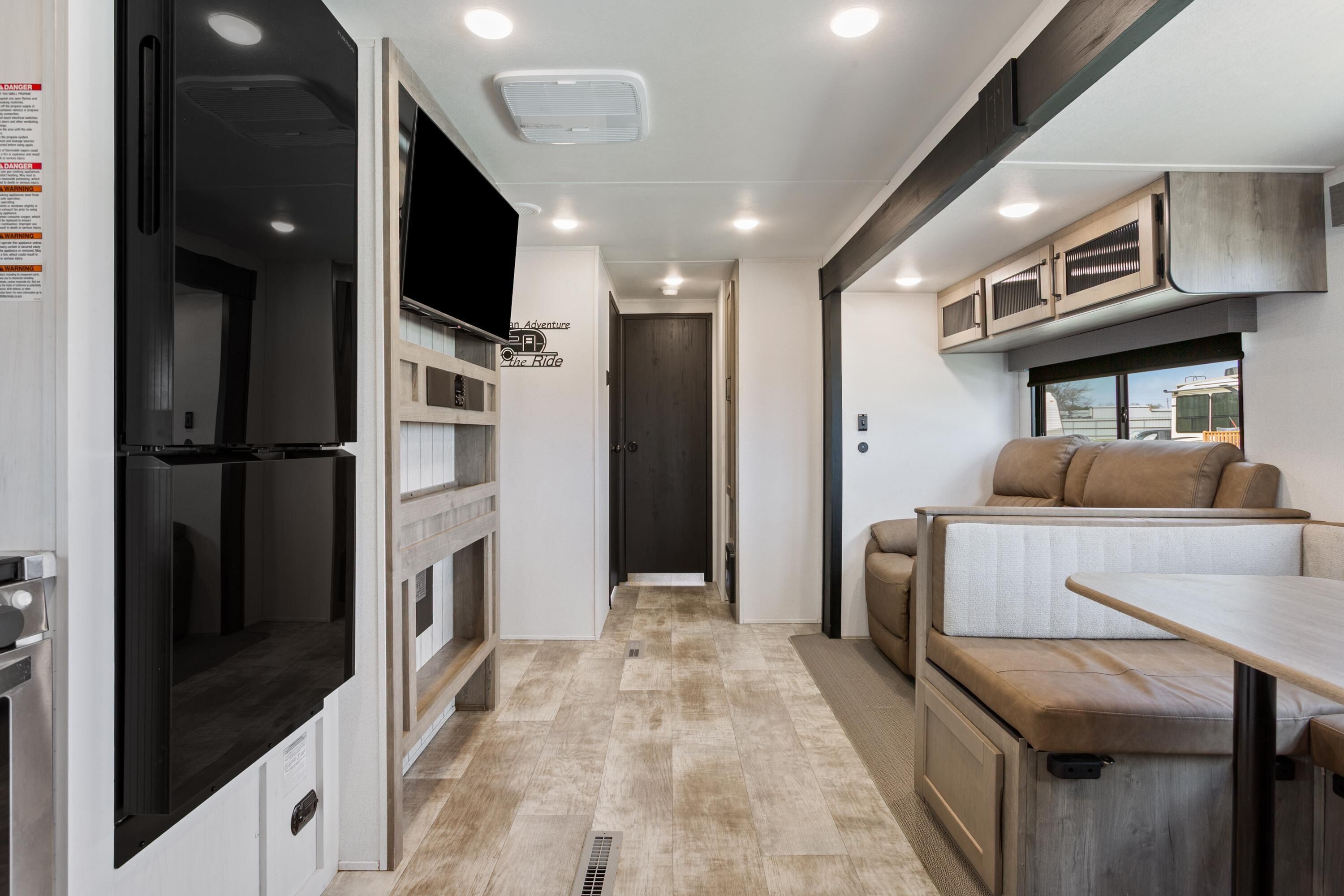 A compact RV interior with a kitchenette, a seating area, and a small table.