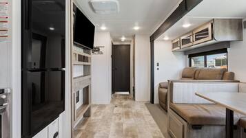 A compact RV interior with a kitchenette, a seating area, and a small table.