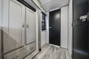 Ein Flur mit Schrank, Tür und einem Fenster mit Jalousien.