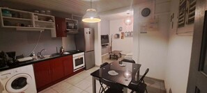 A compact kitchen with a washing machine, microwave, and a dining area with a table and chairs. - Less than 5 minutes to the beach. A relaxing stay with local services. (Schœlcher)