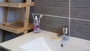 Ein Badezimmer mit einem weißen Waschbecken, Holzregalen und einem Spiegel.