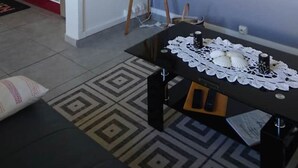 Ein Wohnzimmer mit einem schwarzen Couchtisch, einer grauen Stehlampe und einem Fernseher an der Wand.