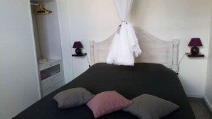 Ein Schlafzimmer mit Bett, Nachttischlampen, einem Kleiderschrank und einem Himmelszelt.
