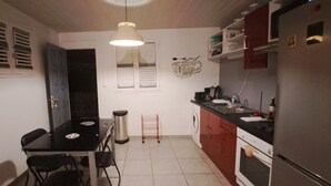 Eine kleine Küche mit Esstisch, Stühlen, Kühlschrank und Waschmaschine.