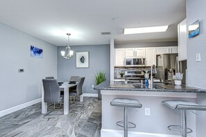 Una cocina moderna con una isla central, taburetes de bar y un comedor con mesa y sillas.