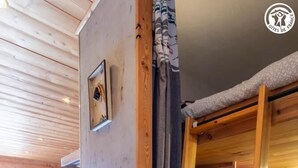 Een houten interieur met een ladder, planken en een deur die uitkomt op een buitengebied.