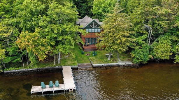 A lakeside cabin with a dock, surrounded by dense trees. - 4th Lake Getaway, Screened Porch, Large Deck & Private Dock (Old Forge)
