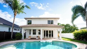 A two-story house with a swimming pool, a covered patio, and a fenced backyard. - NEW Luxe Wellness Retreat - Private Gym, Pilates, Sauna, Pool (Delray Beach)