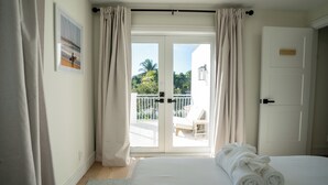 A bedroom with a large bed, a view of the balcony, and a door with a nameplate. - NEW Luxe Wellness Retreat - Private Gym, Pilates, Sauna, Pool (Delray Beach)