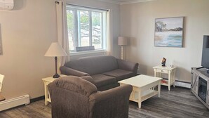 Un salon avec un canapé, une petite table, une lampe et un tableau au mur.