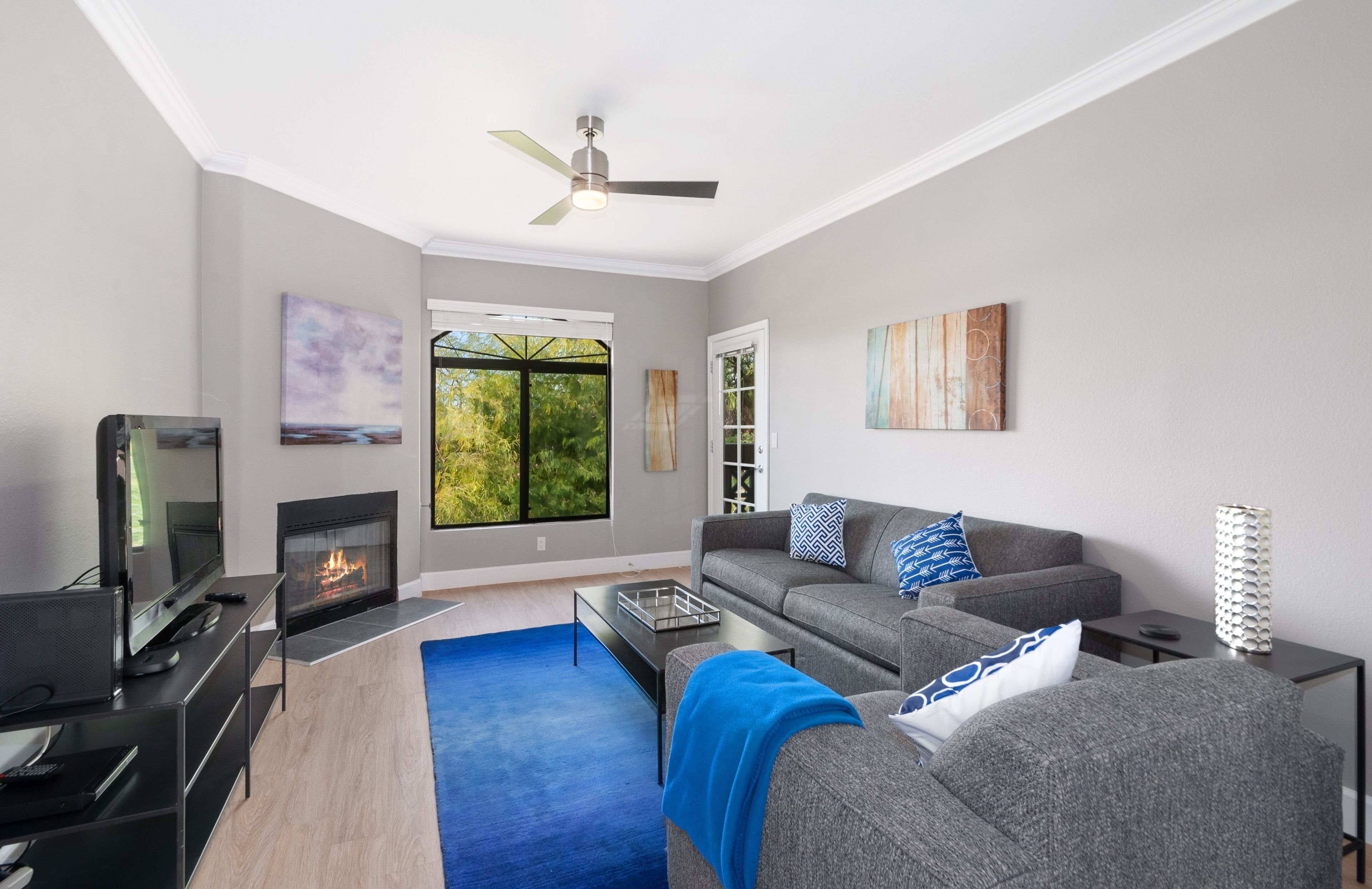 A modern living room with a fireplace, a sofa, a TV, and artwork on the walls.