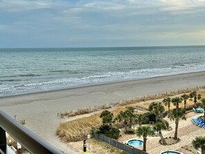 A beach view with a fenced area, palm trees, and lounge chairs. - 1Br sleeps 4 Spacious beach getaway 746 (Myrtle Beach)