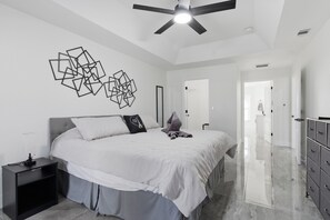 Ein modernes Schlafzimmer mit Bett, Nachttisch und Kommode.