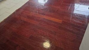 Una cocina con electrodomésticos blancos, una mesa de comedor con sillas y suelo de madera rojo.