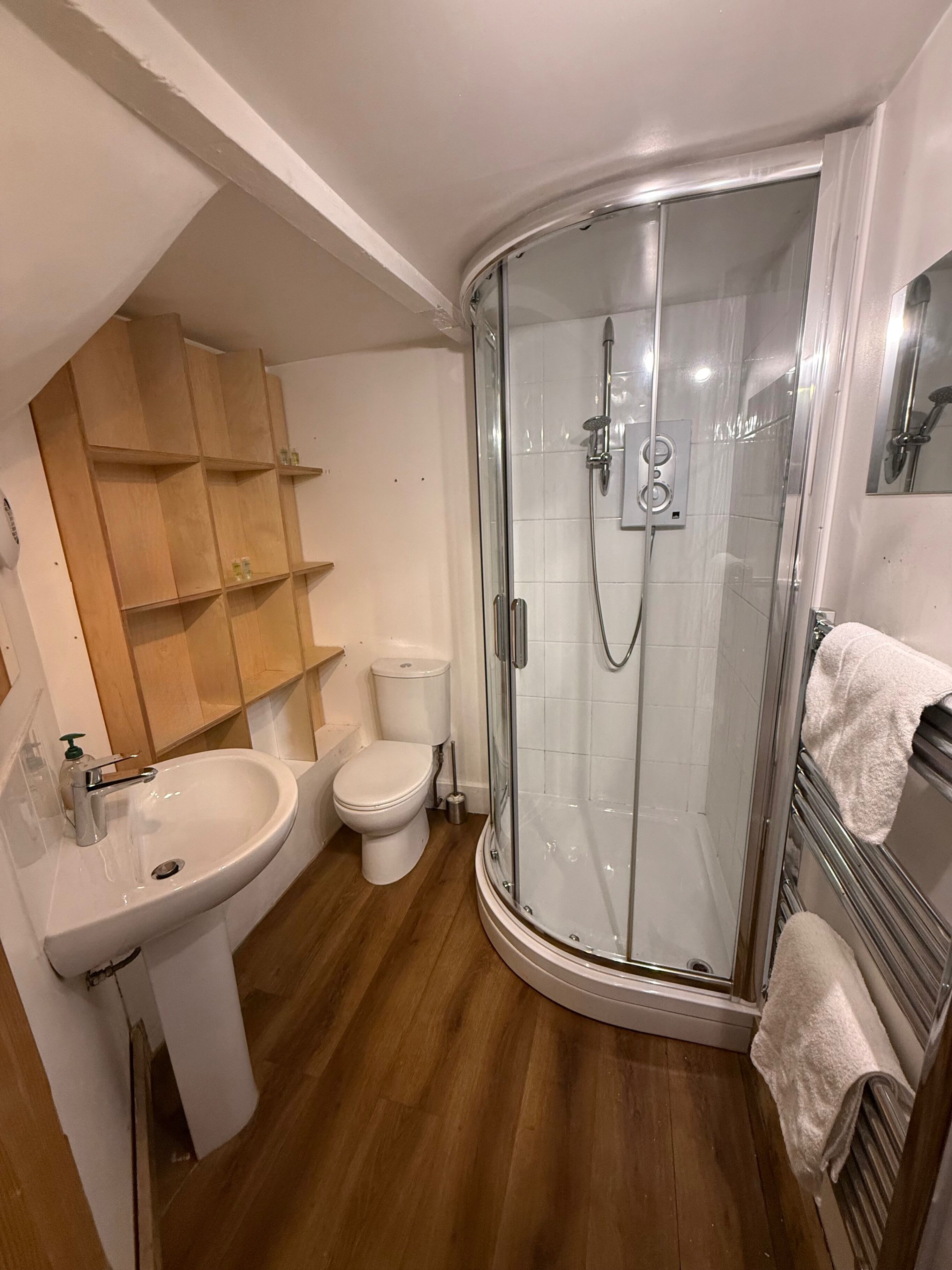 A modern bathroom with a glass-enclosed shower, a white sink, and a toilet.