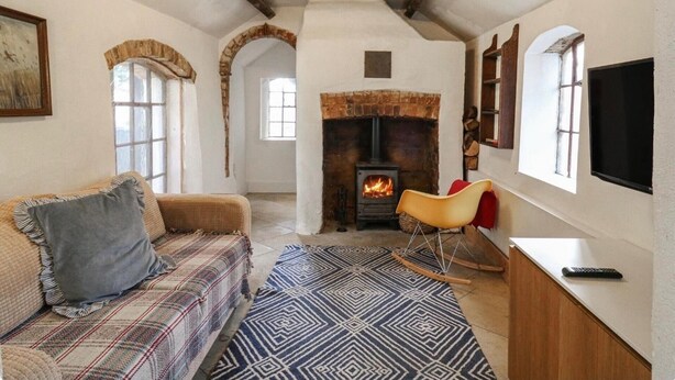 Una sala de estar acogedora con chimenea, un sofá, un sillón mecedora y un televisor.