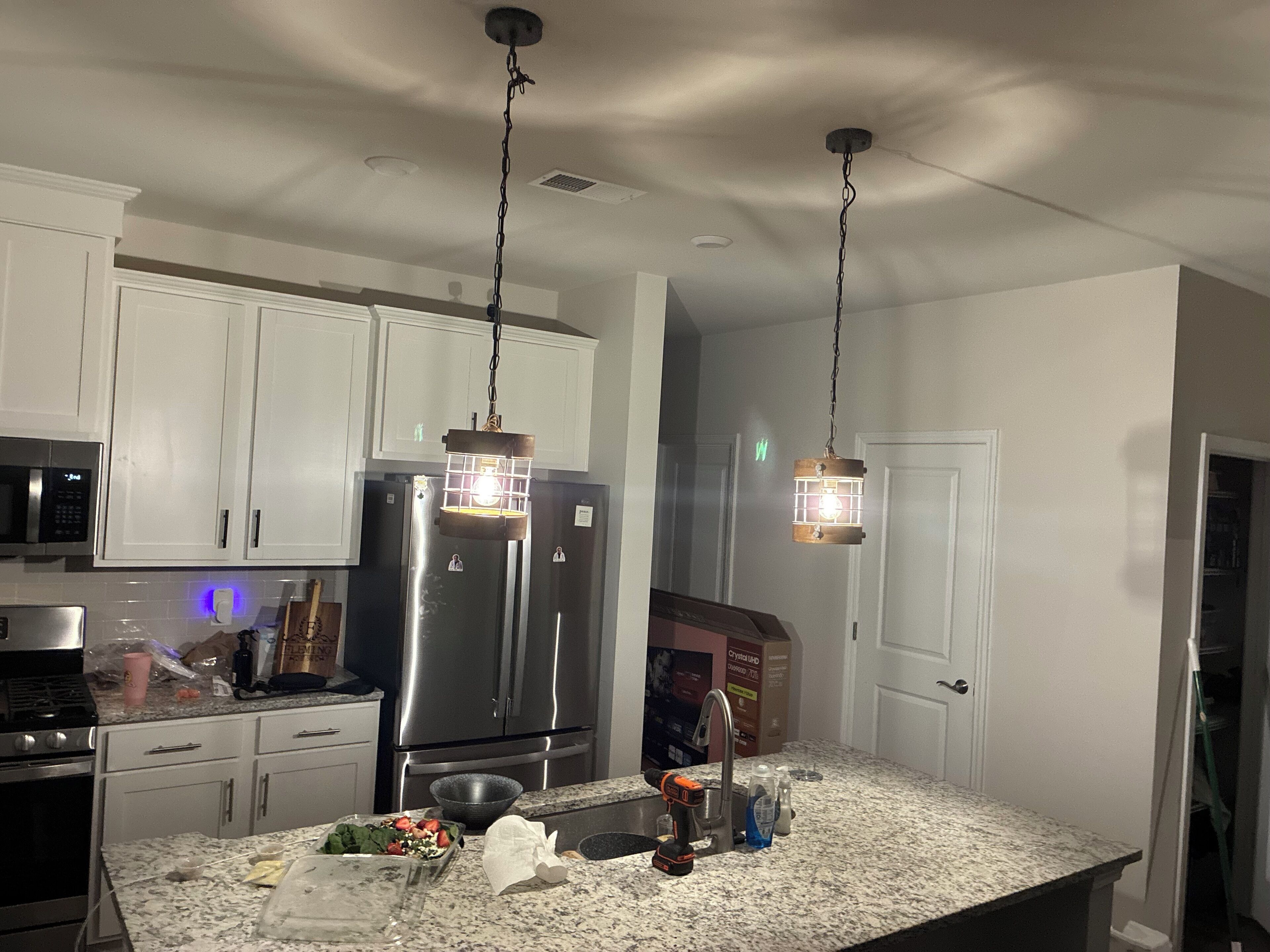 A kitchen with white cabinets, stainless steel appliances, granite countertops, and pendant lighting.