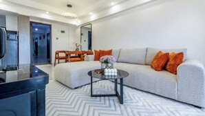 Ein modernes Wohnzimmer mit Sofa, Couchtisch und einem Essbereich mit Stühlen und Tisch.