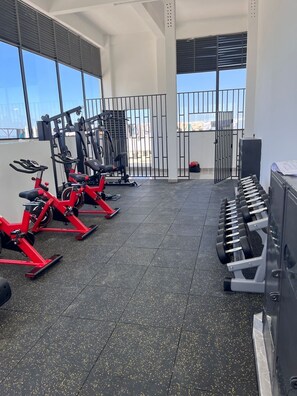 A gym with exercise bikes, a treadmill, and dumbbells. - Riara one residency (Nairobi)