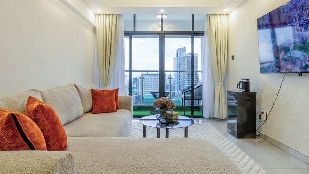 Ein modernes Wohnzimmer mit einer Couch, einem Couchtisch und einem großen Fenster mit Blick auf die Stadt.
