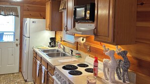 Una cucina in legno con frigorifero, fornello, microonde e lavello.