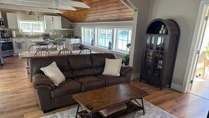 A living room with a brown sofa, a wooden coffee table, and a patterned rug. - Waterfront Family Getaway with Sunroom & Stunning Views (Washington)