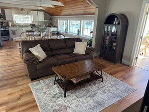 A living room with a brown sofa, a wooden coffee table, and a patterned rug. - Waterfront Family Getaway with Sunroom & Stunning Views (Washington)