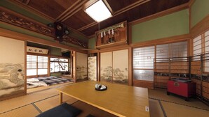 Ein traditioneller japanischer Raum mit Tatami-Bodenbelag, einem niedrigen Holztisch, Schiebetüren mit Shoji-Bildschirmen und einem roten Schrank.