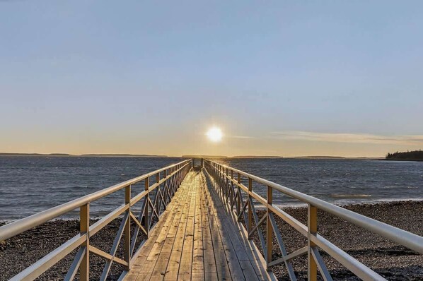 A wooden pier leading to a beach with a clear sky and the sun setting or rising in the distance. - Evergreen Cabin Ocean Front Acadia A Frame Studio (Tremont)