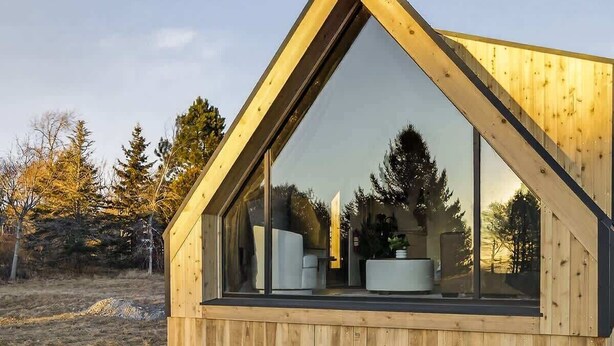 A modern wooden cabin with a triangular roof, large windows, and a visible interior with a white chair and a round table. - Evergreen Cabin Ocean Front Acadia A Frame Studio (Tremont)