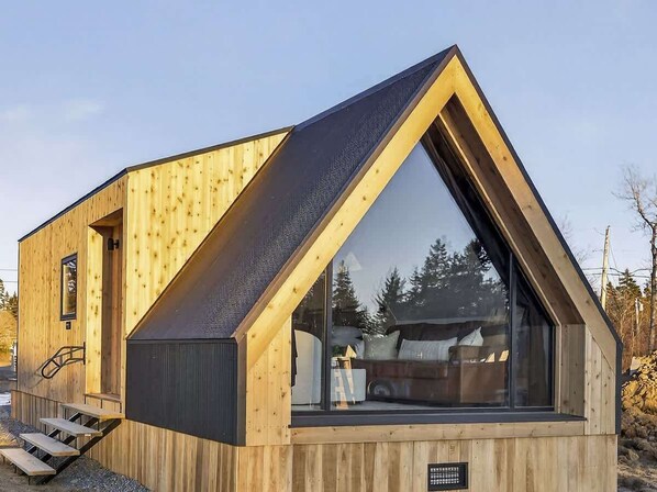 A modern wooden cabin with a triangular roof, large windows, and a staircase leading to the entrance. - Evergreen Cabin Ocean Front Acadia A Frame Studio (Tremont)