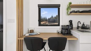 A modern kitchen with a window, a coffee maker, and a sink. - Sunset Oceanfront Cabin with Sauna, Beach and Dock (Tremont)