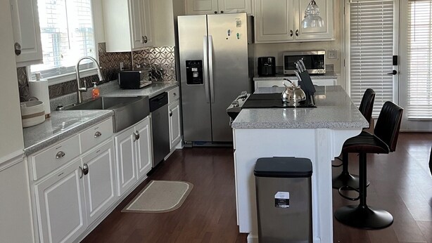A modern kitchen with white cabinetry, stainless steel appliances, and a central island with bar stools. - Quiet Pines by Abner.
Welcome to our small cottage retreat among the pines. (Valley)