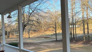 A covered porch with white railings and a view of a wooded area. - Quiet Pines by Abner.
Welcome to our small cottage retreat among the pines. (Valley)