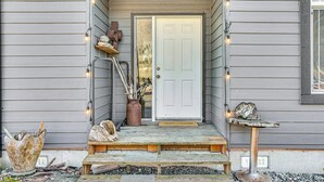 A wooden porch with a welcome mat, a bird bath, and decorative items. - Nature Art Retreat on Breckenridge Creek w/ Pond! (Sumas)