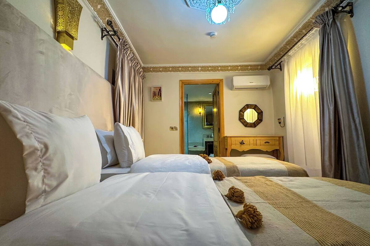A hotel room with two beds, a wooden dresser, a mirror, and a ceiling light fixture.