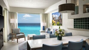 Ein Hotelzimmer mit großem Balkon, einer Essecke und einem Wohnbereich mit Blick auf den Ozean.