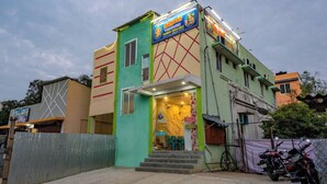 Un immeuble à plusieurs étages, doté d’une façade verte et beige, sur lequel on peut voir une enseigne indiquant que des chambres sont disponibles à la location.