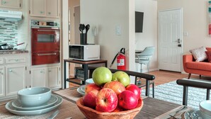 Una cocina con una mesa de madera, un cuenco de manzanas y un microondas.