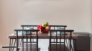 Una mesa de comedor con frutero, platos y cubiertos.