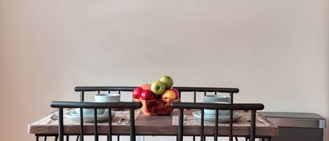 A dining table with a fruit bowl, plates, and cutlery.