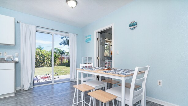 Une cuisine moderne avec un coin repas, des meubles blancs et une vue sur l’extérieur.