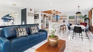 A modern living room with a blue sofa, a wooden coffee table, and a potted plant.